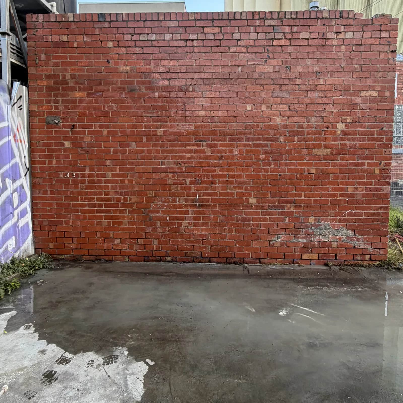 The same brick wall with the graffiti gone and clean brick showing